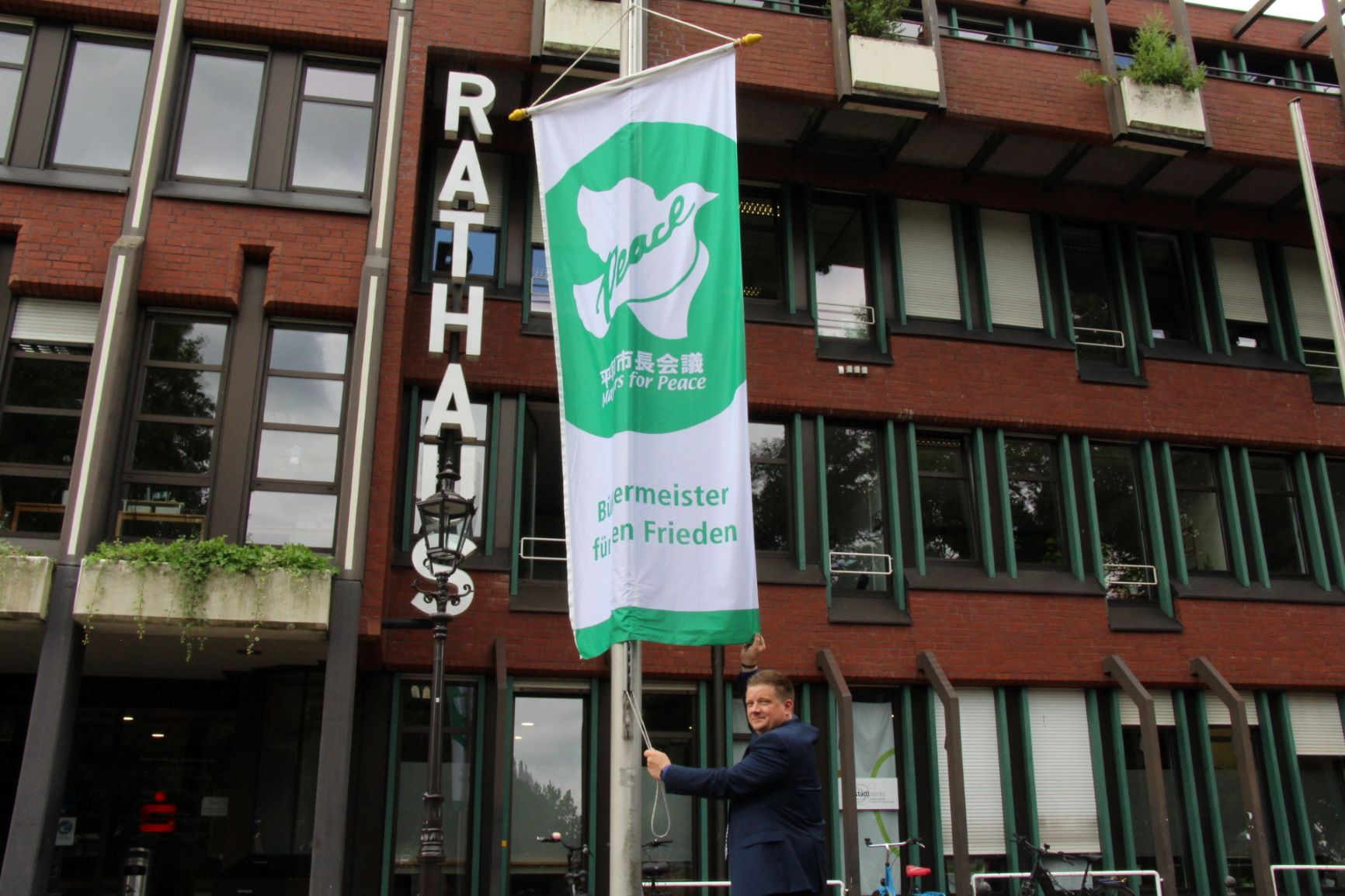 Bürgermeister mit Mayor for Peace Flagge