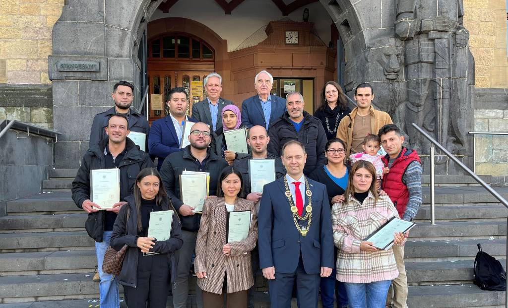 18 Neubürger*innen erhielten ihre Einbürgerungsurkunden aus den Händen des stellvertretenden Bürgermeisters Andreas Leib (vorn).