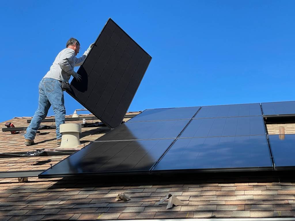Mann montiert eine Fotovoltaik-Anlage auf einem Dach. Foto: Bill Mead/unsplash