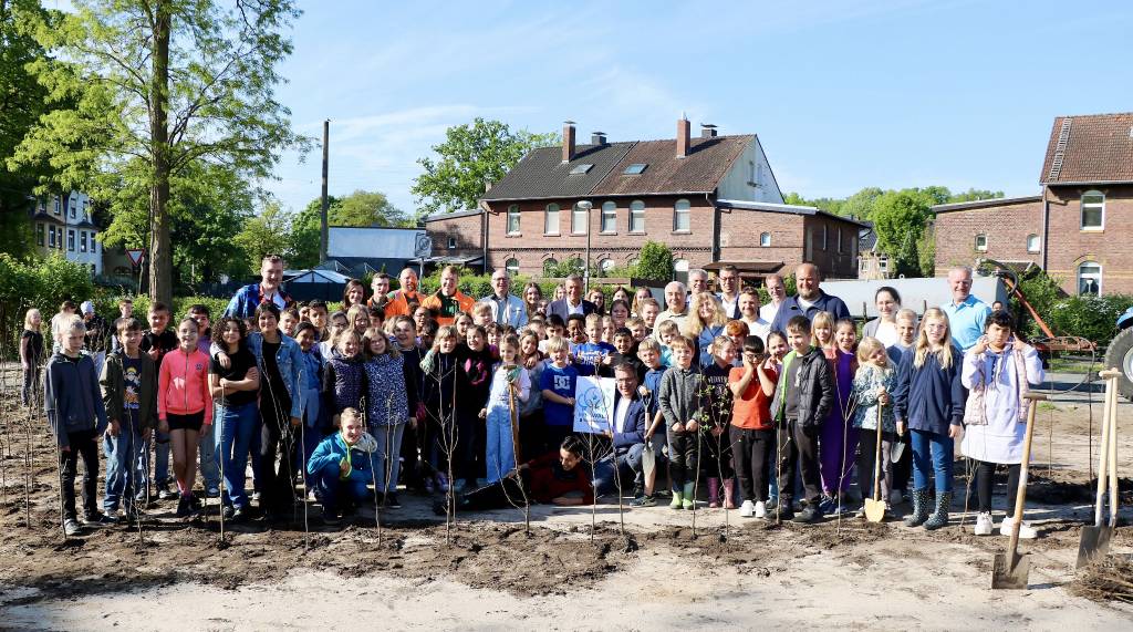 Bürgermeister Christoph Tesch sowie Vertreter*innen der Verwaltung, der Lokalpolitik, der Zukunftsinitiative Klima.Werk, der KSR und der Grundschule Hochlarmark stehen hier mitten im „Tiny Forest“, den viele helfende Hände in Windeseile an der Ecke Westfalenstraße/Hüserstraße pflanzten. Foto: Stadt RE 